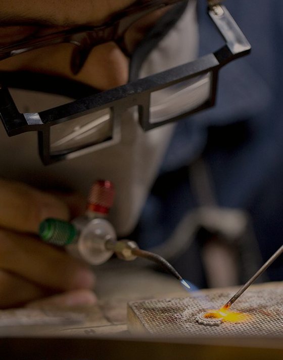 A BVLA jeweller at the bench, a torch on a small gold piece