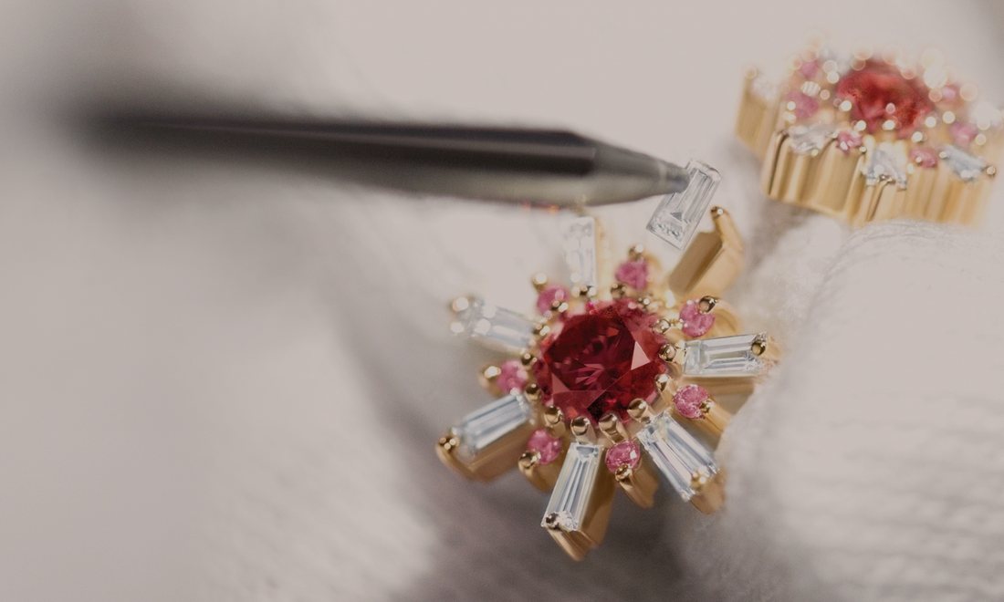 Two gold pieces set with red stones, held in tweezers