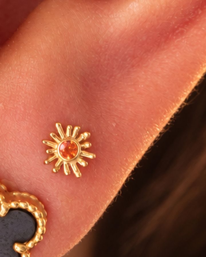 A small gold sunray with a topaz, worn in a lobe