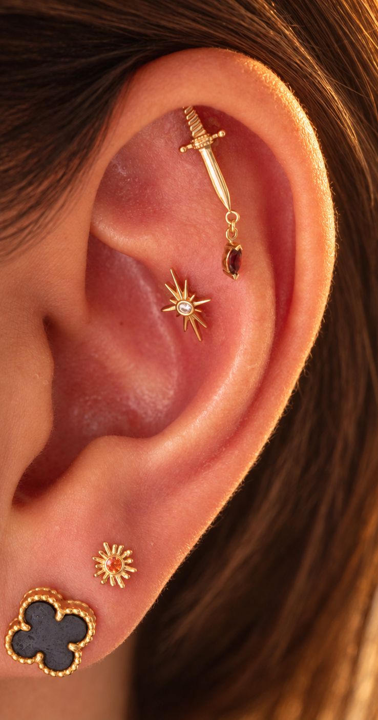 An ear finished in gold, with pieces on the helix, conch and lobe